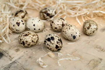 quail eggs scattered on a wooden surface surrounded by straw,