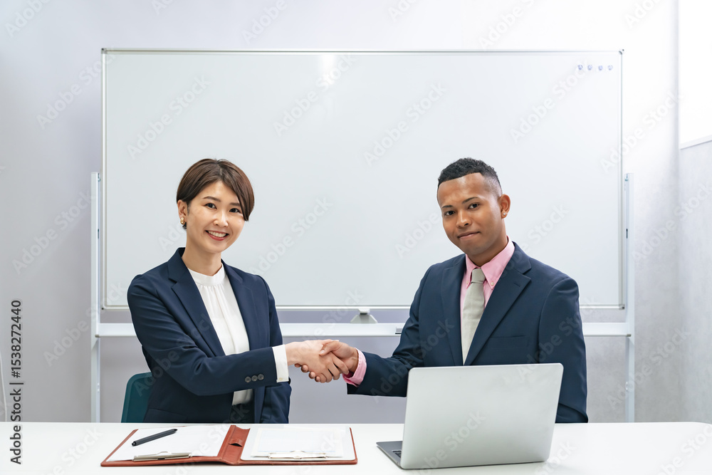 Poster ホワイトボードの前で握手する黒人男性ビジネスマンと日本人女性スタッフ