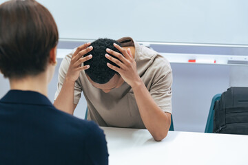 悩む黒人男性と面談する日本人女性スタッフ