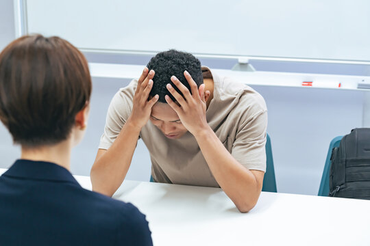 A Japanese female staff member interviewing a troubled black man