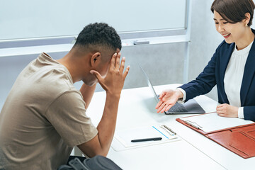 A Japanese female staff member interviewing a troubled black man