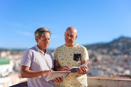 gay senior couple using tablet in a rooftop