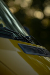 A detailed close up of a bright yellow car featuring a windshield wiper