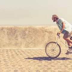 Acrylic prints Man is cycling on white bicycle wearing straw hat along hexagonal stone promenade beside sea