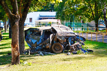 Accident scene with destroyed car on lawn, aftermath of fatal crash with extreme vehicle damage....