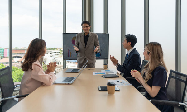 Enthusiastic diverse corporate team applauding in a meeting around a conference table, embodying collective decision making. - Powered by Adobe