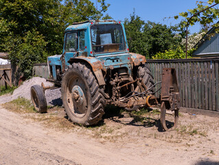 A blue tractor sitting on top of a dirt road