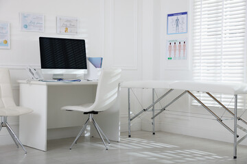 Doctor's workplace with modern computer and examination table in medical office