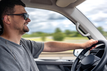 Smiling man driving car. Relaxed road trip. Driver in motion.