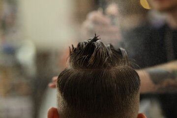Professional barber making stylish haircut in barbershop, closeup