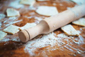 Rustic wooden rolling pin on floured table with homemade dough pieces. Perfect for baking blogs, cookbooks, or artisan kitchen ads. Warm, inviting, and authentic baking atmosphere.