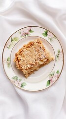 A delectable Apple Crumble: A rustic, golden-brown baked dessert with a crispy oat topping and juicy apple filling, served on an elegant floral plate. Perfect for autumn and winter seasons.