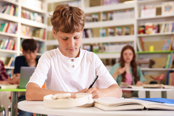 Student with books studying at table in library