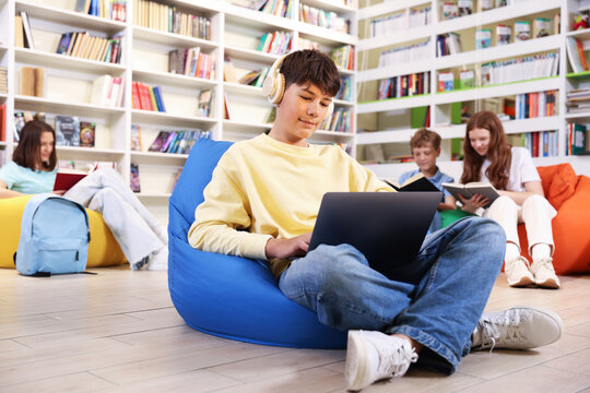 Student with laptop studying on bean bag in library