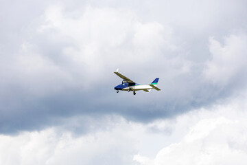 Light aircraft flying in mid-air against a background of dramatic clouds. General aviation concept, transportation, private flight.