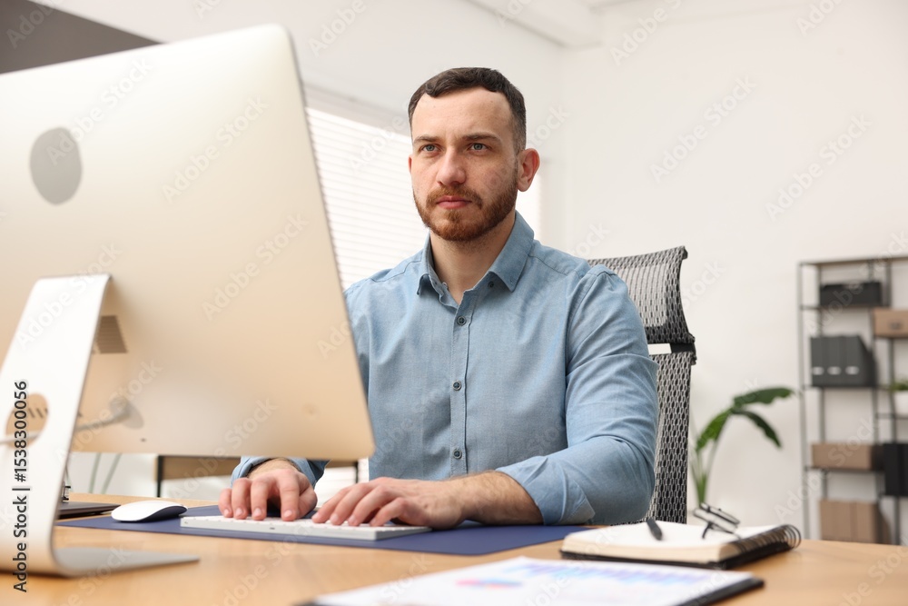 Poster man working on computer at desk in office