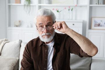 Senior man with vision problem on sofa at home