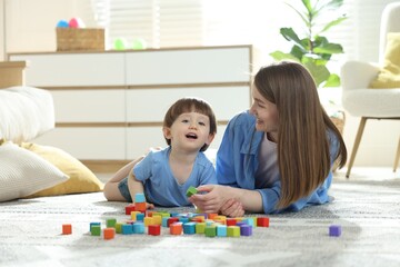 Naklejka premium Mother and son playing with colorful cubes at home. Space for text