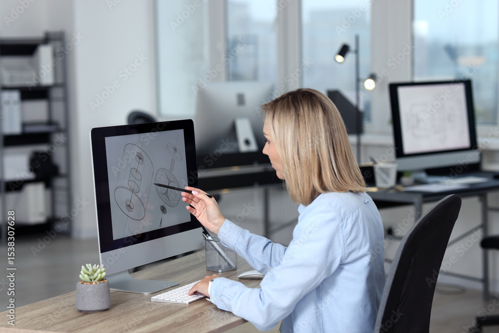 Poster technician making digital engineering drawing on computer at desk in office