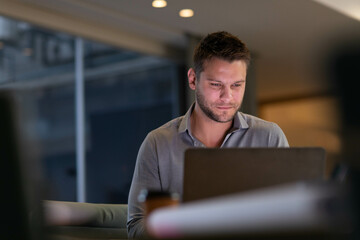 Man typing on laptop computer at modern office lounge table with takeaway coffee cup