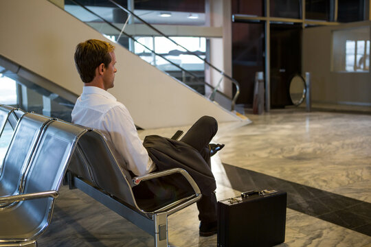 Black briefcase is resting on polished marble floor beside metal bench chairs in terminal hall