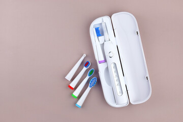 Modern electric ultrasonic toothbrush with rechargeable battery on a gray surface.