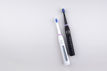 Modern electric ultrasonic toothbrush with rechargeable battery on a gray surface.