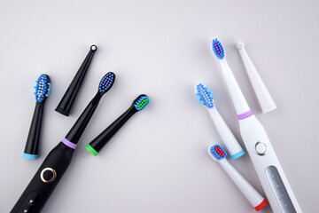 Modern electric ultrasonic toothbrush with rechargeable battery on a gray surface.