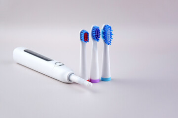 Modern electric ultrasonic toothbrush with rechargeable battery on a gray surface.
