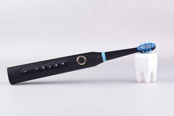 Modern electric ultrasonic toothbrush with rechargeable battery on a gray surface.