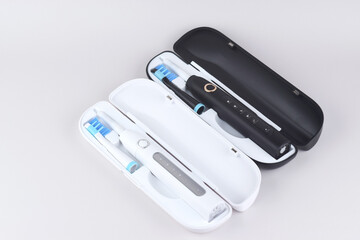Modern electric ultrasonic toothbrush with rechargeable battery on a gray surface.