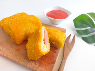 Close-up of crispy fried mayonnaise risoles filled with ham, egg, and cheese, served on a wooden...