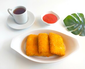 Close-up of crispy fried mayonnaise risoles filled with ham, egg, and cheese, served on a wooden board with a small bowl of pink dipping sauce. Risol mayo.