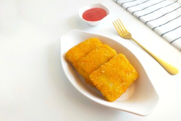 Close-up of crispy fried mayonnaise risoles filled with ham, egg, and cheese, served on a wooden board with a small bowl of pink dipping sauce.