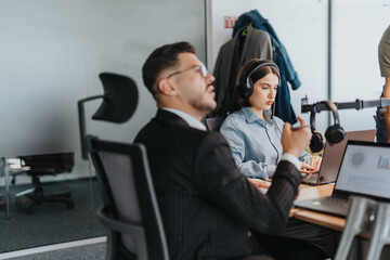A diverse group of business people engaging in a collaborative meeting. They're discussing ideas and working together using laptops and audio equipment in a contemporary office setting.
