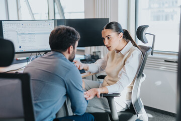 Two multicultural employees engaged in a focused discussion at a modern office desk, highlighting...