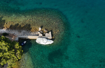 Aerial drone photo of a vacation boat in turquoise water next to a jetty in Croatia. Photography for background, postcards, wallpapers.