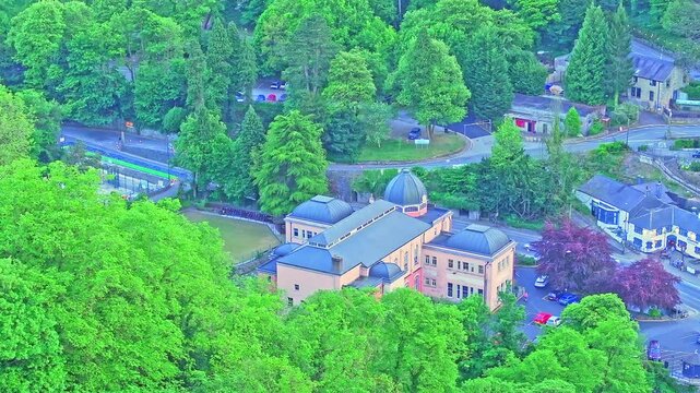 Elevated drone footage shows the Grand Pavilion of Matlock Bath nestled in thick woodland and Victorian roads, highlighting the town&rsquo;s spa heritage and green setting in the Derbyshire Dales.