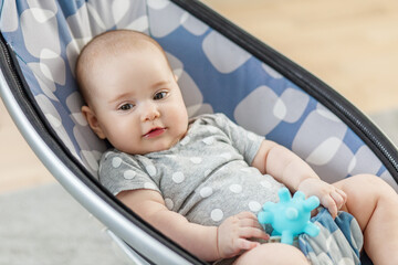 Cute baby playing in modern baby rocker