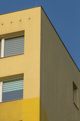 A charming building painted in yellow and white stands under a bright blue sky, creating a picturesque daytime scene