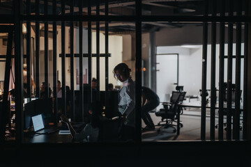 Business coworkers are seen collaborating in a modern office setting, working late into the night....