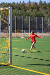 Sporty girl scores a goal into the goal. Football concept. Girl on the football field.
