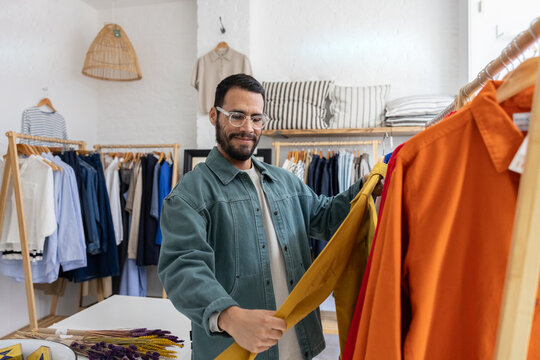 Man Examining Yellow Shirt in Clothing Store