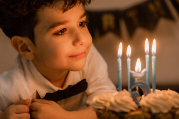 little boy makes a wish and blows out the candles on his birthday cake