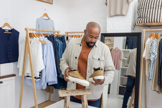 Man Holding Stylish Sneakers in Fashion Store