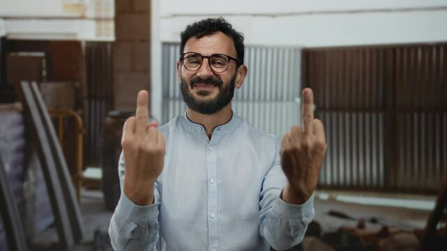Hispanic man with beard and glasses gestures rudely at a construction site, creating a provocative atmosphere.