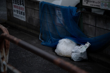 住宅街のゴミ収集所に置かれたゴミ袋と青いネット