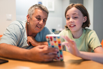Smiling caucasian grandmother and  granddaughter enjoying time together with smartphone. 