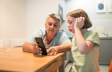 Obraz premium Smiling caucasian grandmother and granddaughter enjoying time together with smartphone. 