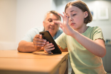 Smiling caucasian grandmother and  granddaughter enjoying time together with smartphone. 